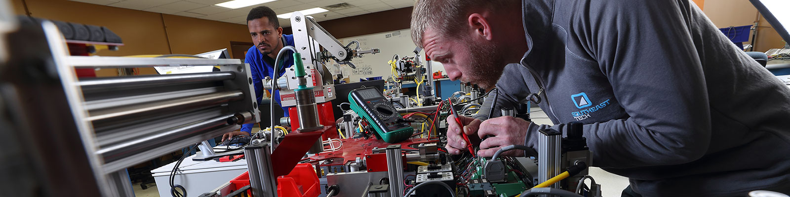 Mechatronics students working on large electronic and robotic project in a classroom