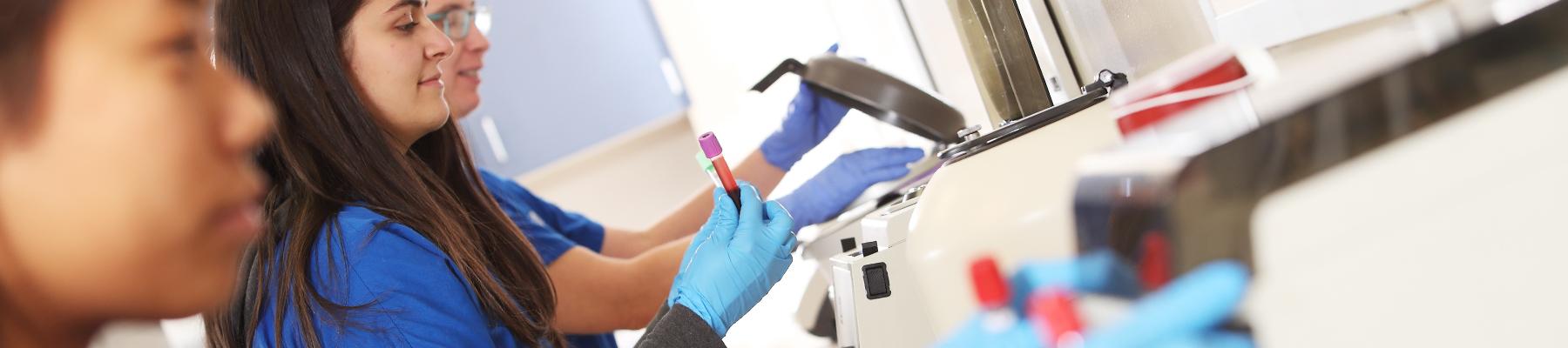 Students spinning vials of blood in machines in lab