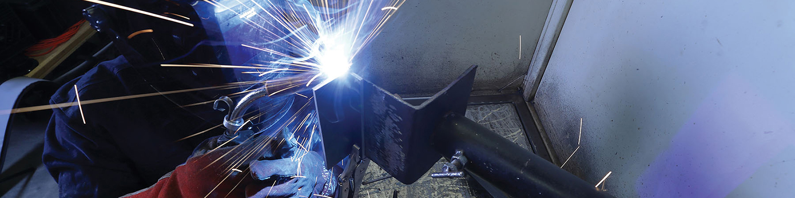 Side view of a Southeast Tech student in welding gloves and mask using a torch on a weld