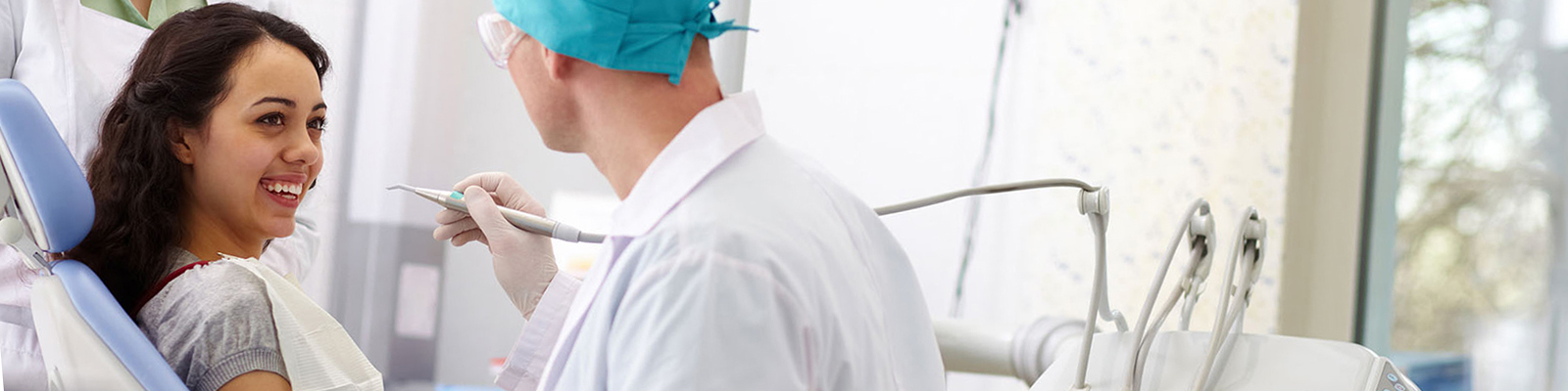 Woman in dental exam room smiling, dentist about to exam