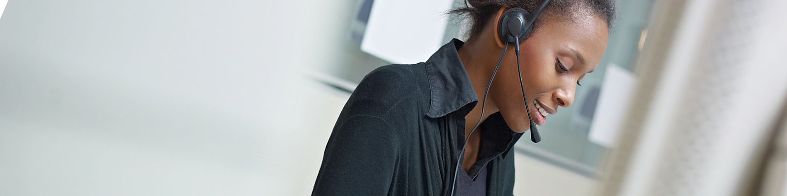 Woman in call center setting wearing a headset and working in front of a computer