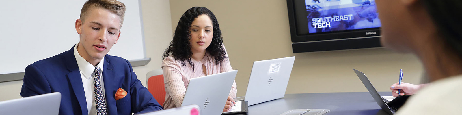 Students in business apparel working at a conference room table