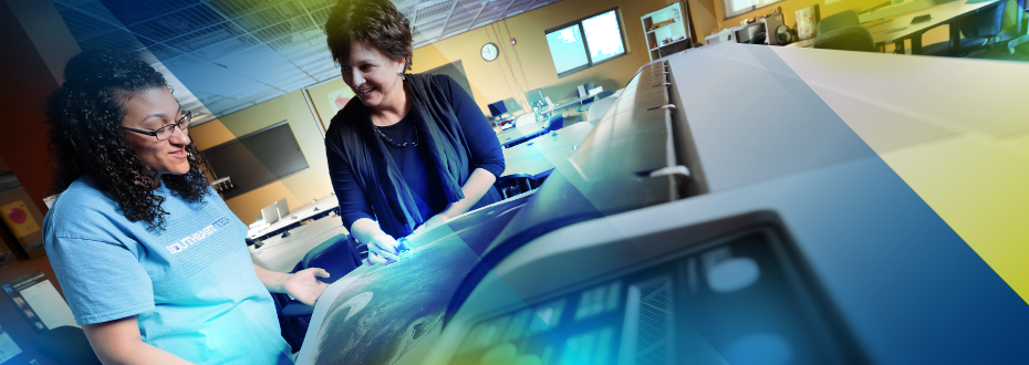 Student and instructor reviewing print from large-scale printer