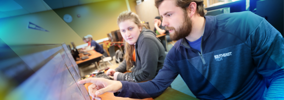 Instructor and student with laptop and auxiliary monitor reviewing CAD design