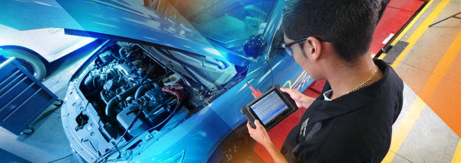 Instructor and students reviewing diagnostics on a blue car with hood up in auto lab